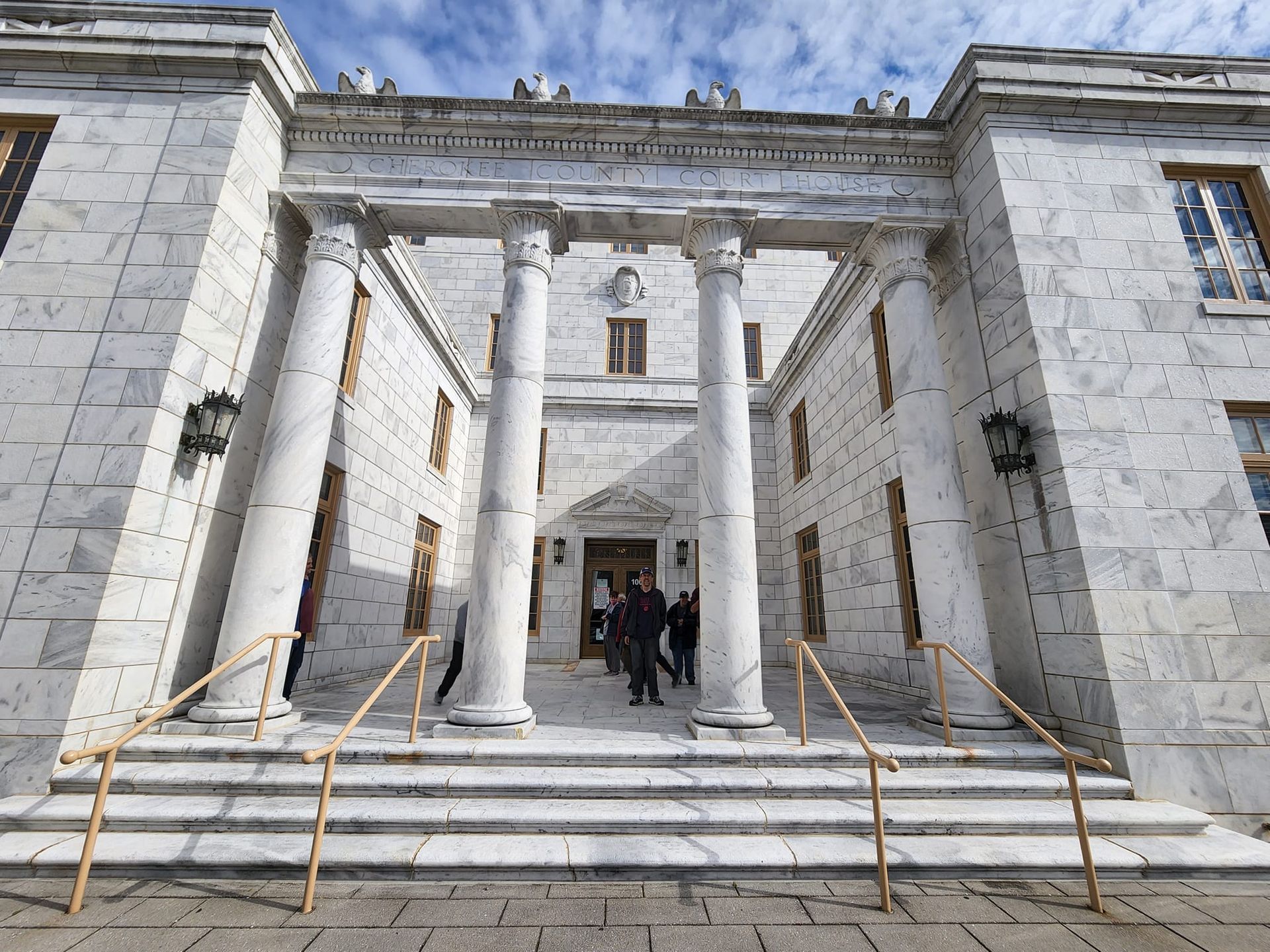 a group of people are standing in front of a large white building with columns .