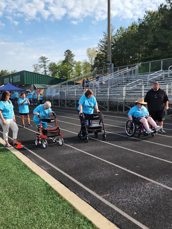 a group of people in wheelchairs and walkers on a track .
