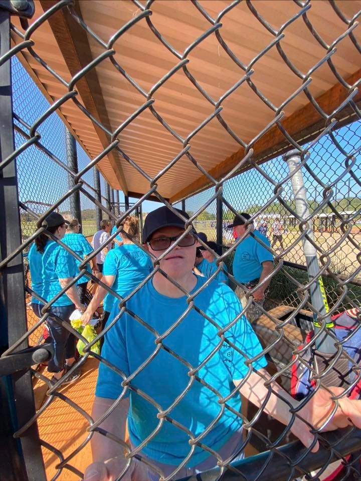 a man in a blue shirt is behind a chain link fence