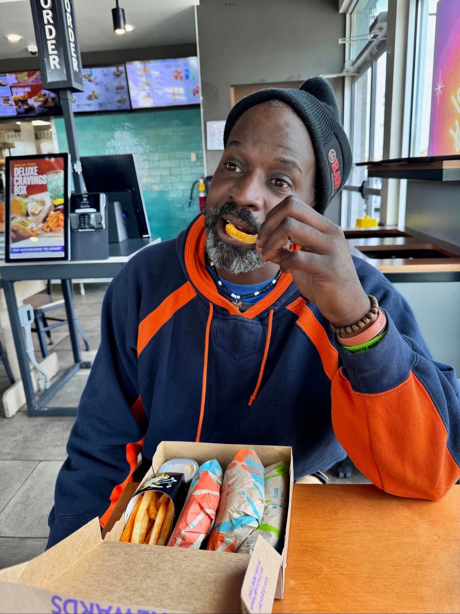 a man is sitting at a table with a box of donuts in front of him