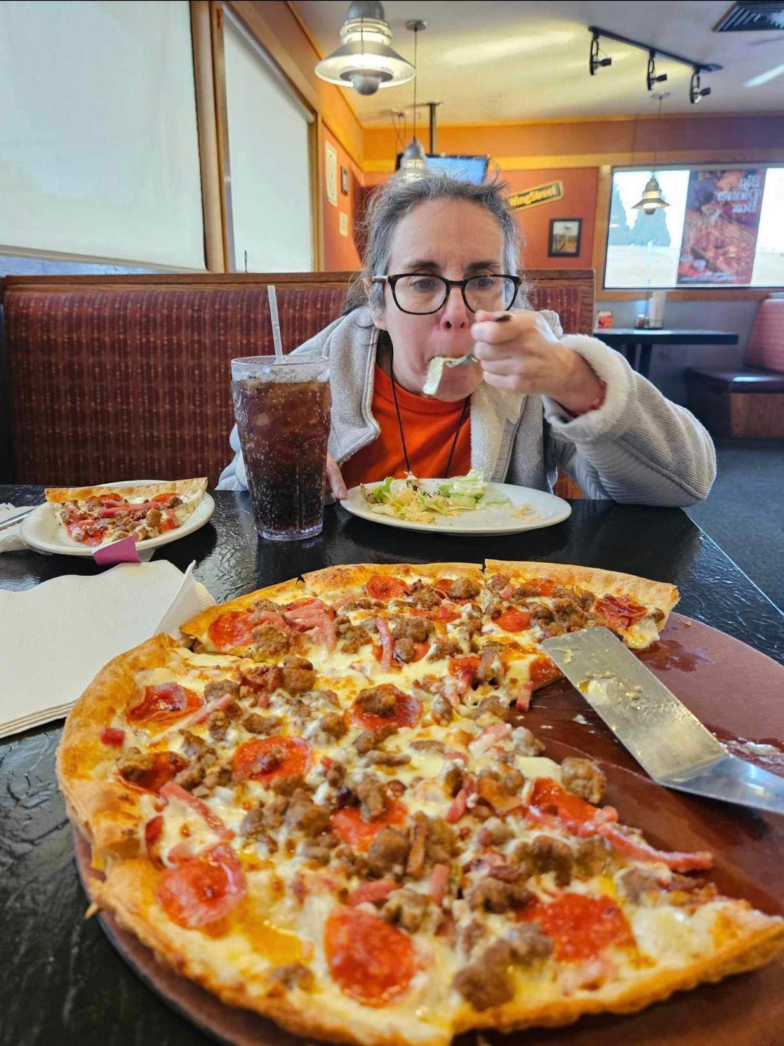 a woman is sitting at a table eating a pizza