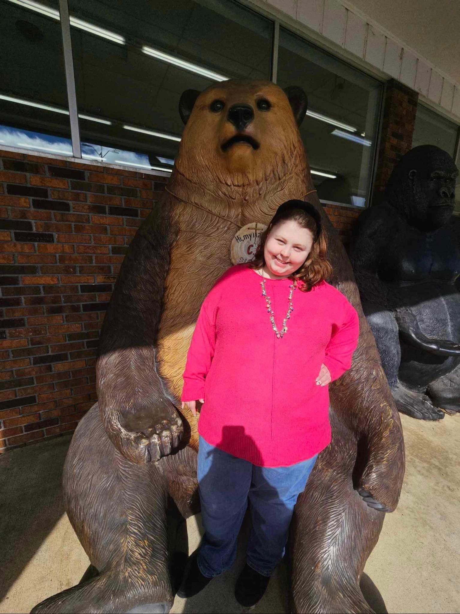 a woman standing next to a statue of a bear