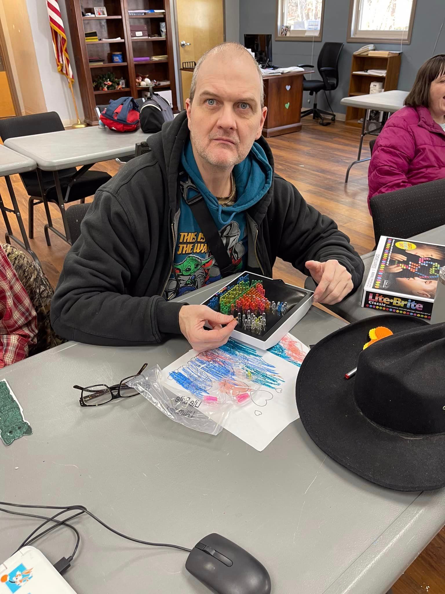 a man is sitting at a table with a hat and a mouse .