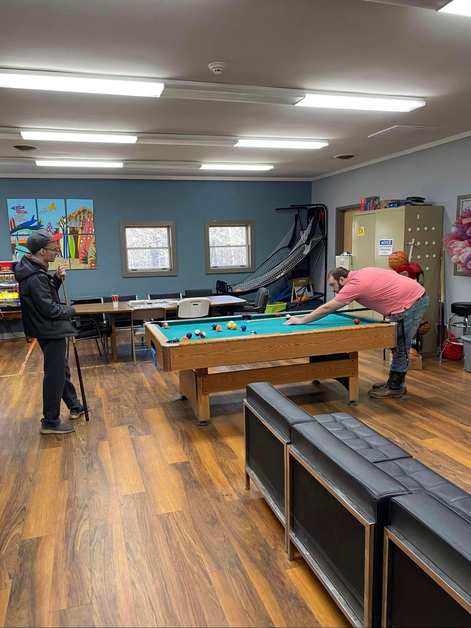 a group of people are playing pool in a room .