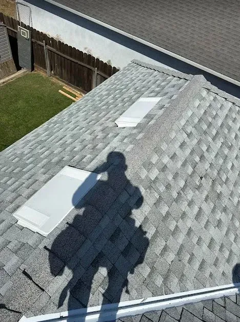 A shadow of a person is cast on the roof of a house.