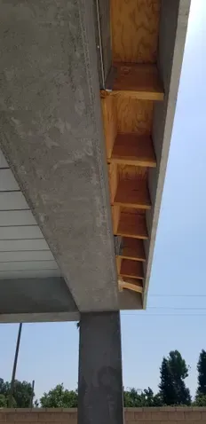 A close up of a concrete structure with wooden shelves underneath it.