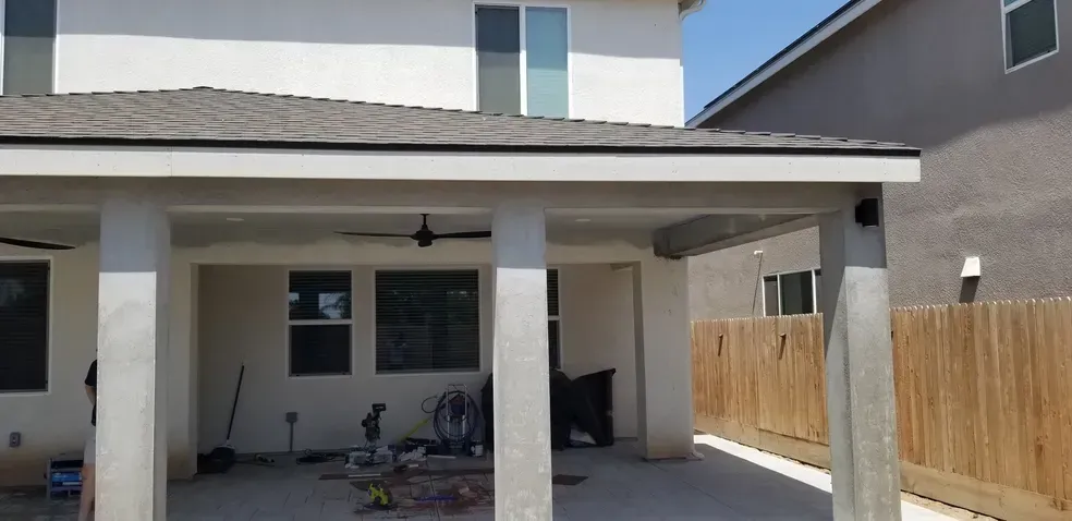 A house with a covered patio and a wooden fence in front of it.