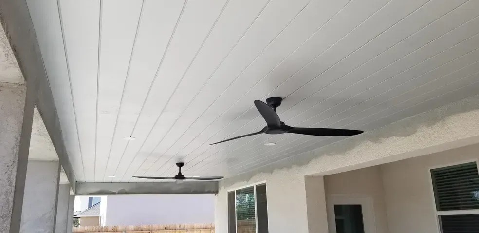 A ceiling fan is hanging from the ceiling of a porch.
