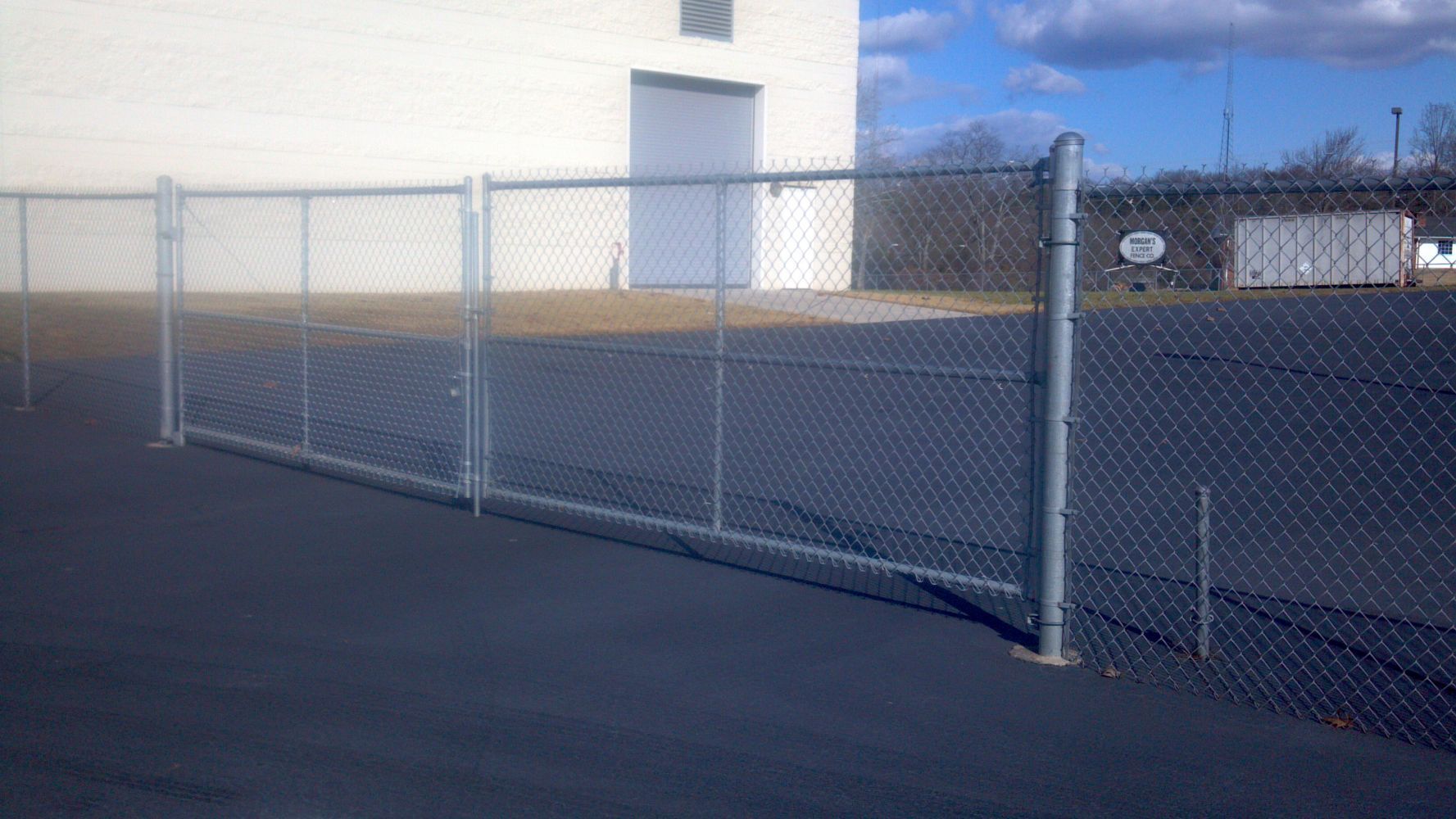 Chain-link fence in front of a building on a sunny day.