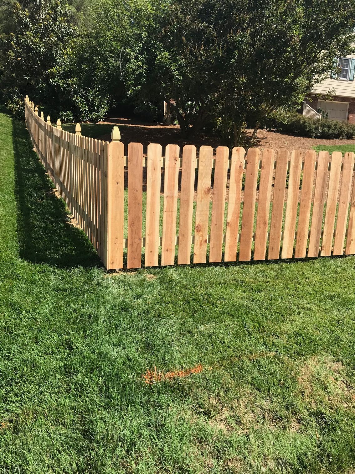 Wooden picket fence on green lawn.