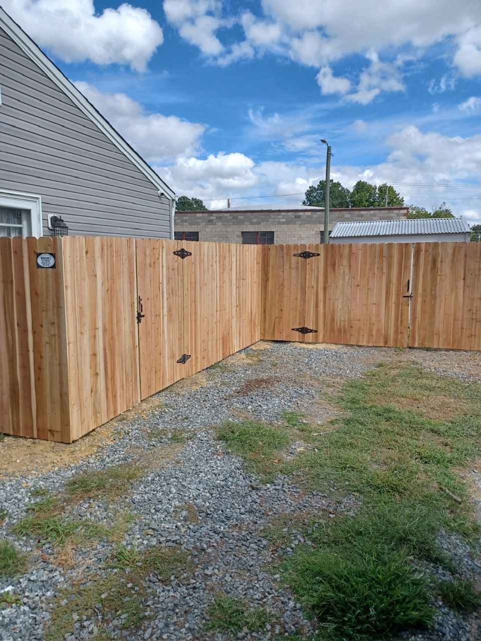 Wooden fence surrounds a yard under a blue sky.