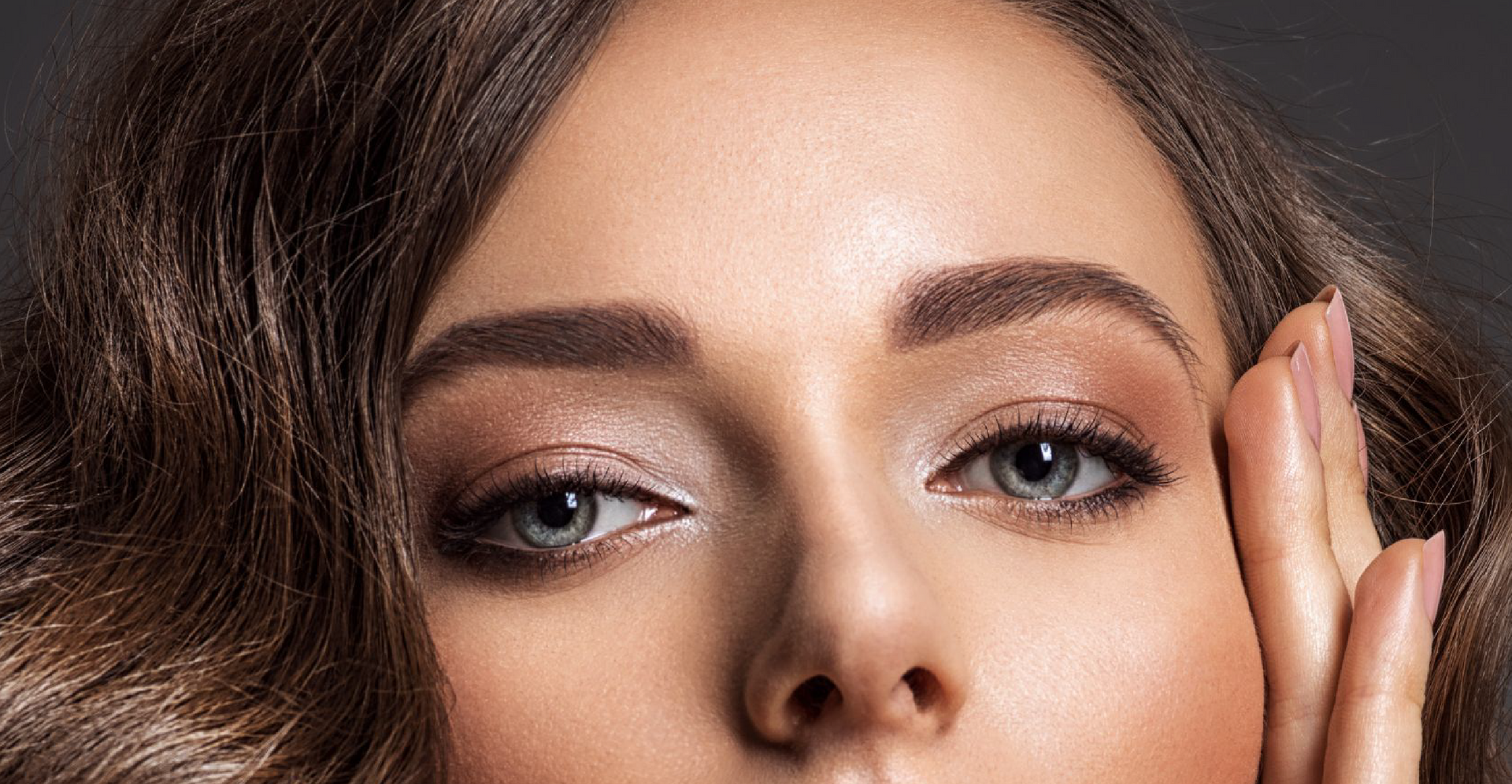 A close up of a woman 's face with her hand on her face.