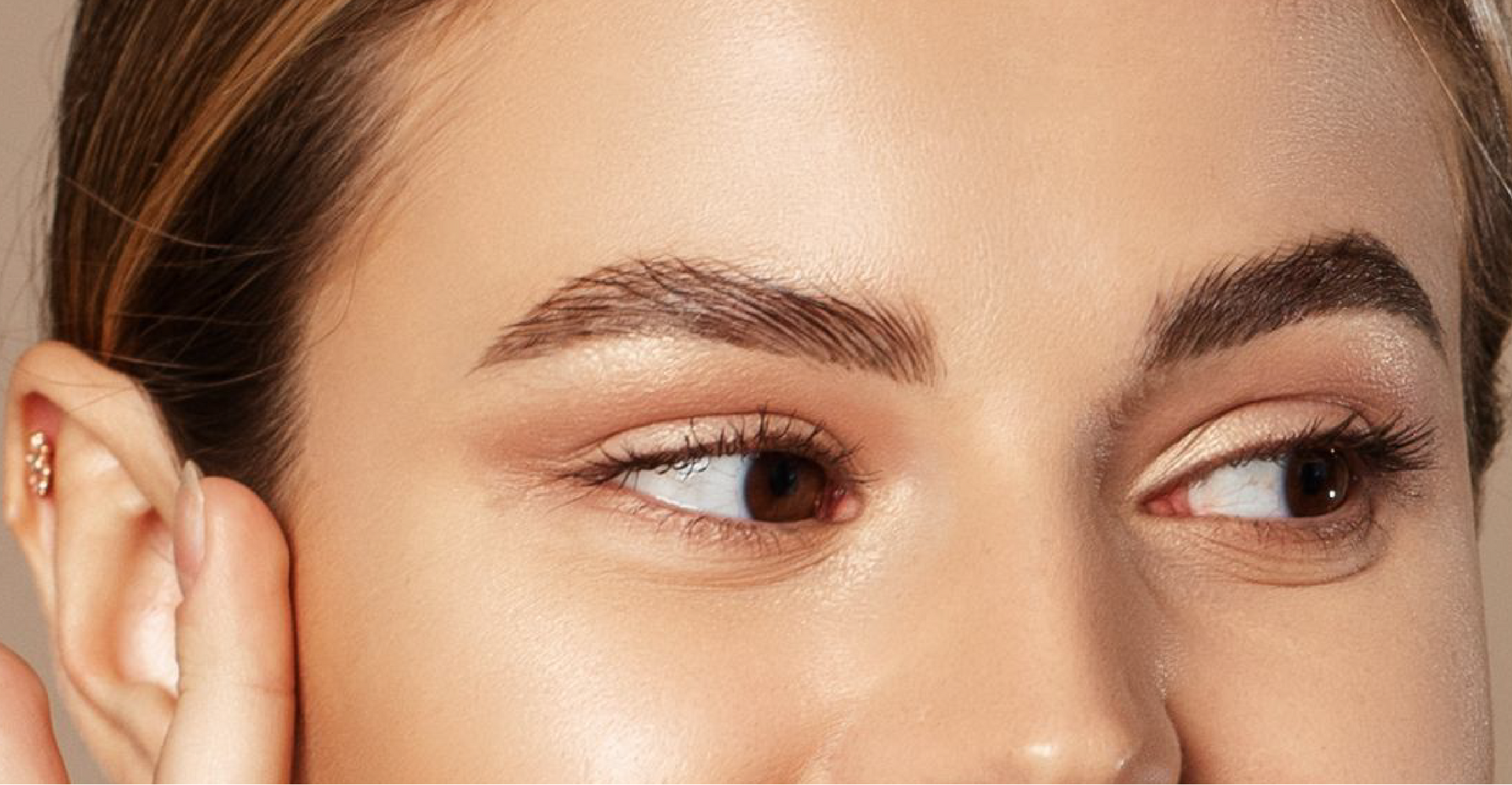 A close up of a woman 's face with her hand on her ear.