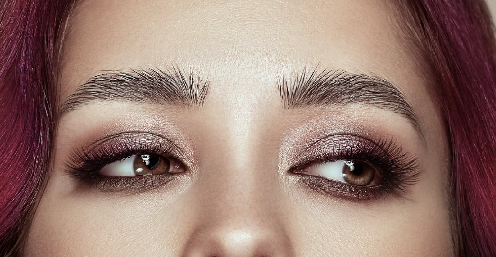 A close up of a woman 's eyes with purple hair.