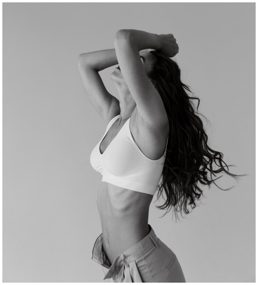 A black and white photo of a woman in a white bra and shorts.