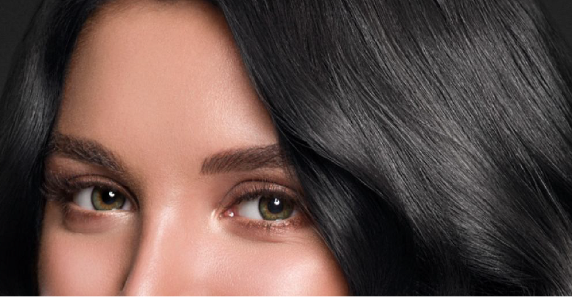 A close up of a woman 's face with black hair and green eyes.