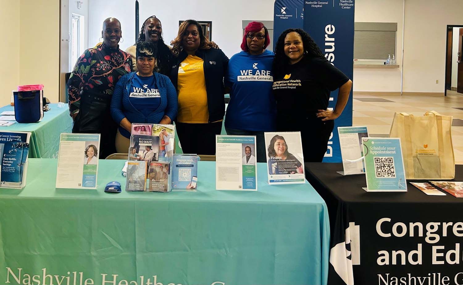 Six people pose behind two tables with Nashville Health signage and informational brochures at an indoor event.