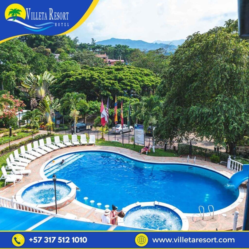 Piscina del Villeta Resort Hotel, rodeada de árboles, con dos jacuzzis y tumbonas.
