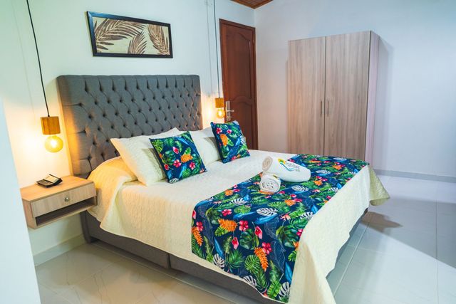Dormitorio con cabecero capitoné, ropa de cama estampada, mesita de noche y armario.
