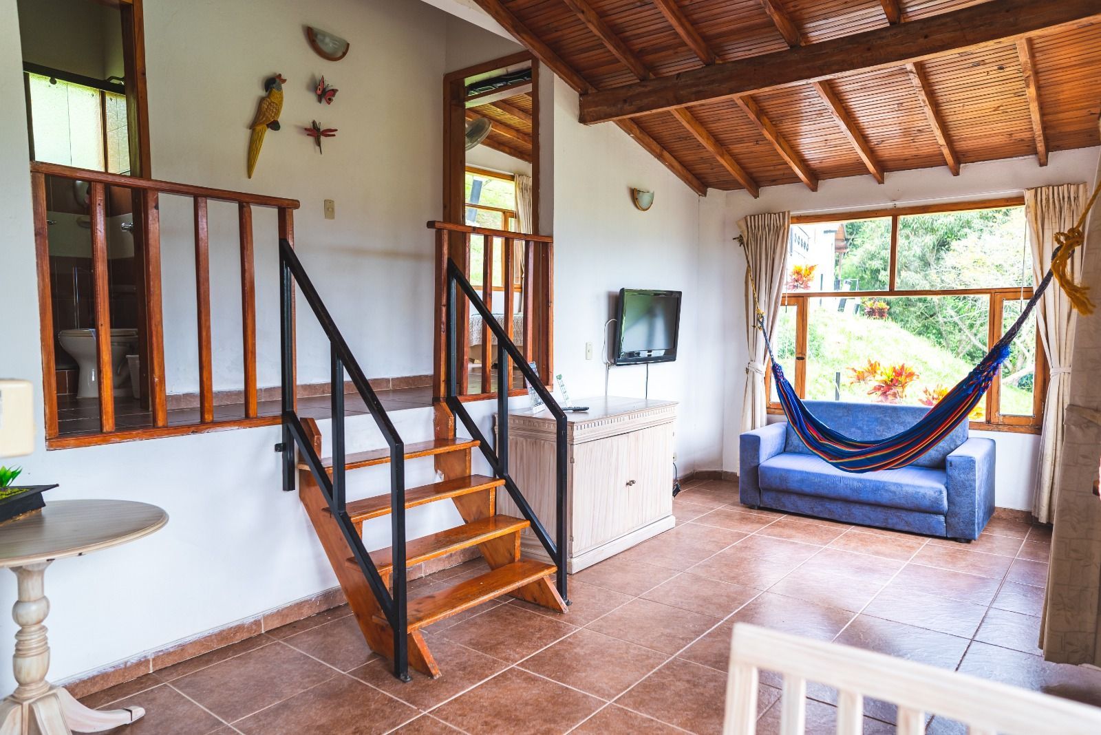 Habitación acogedora con escaleras, un sofá y una hamaca cerca de una ventana con vistas.