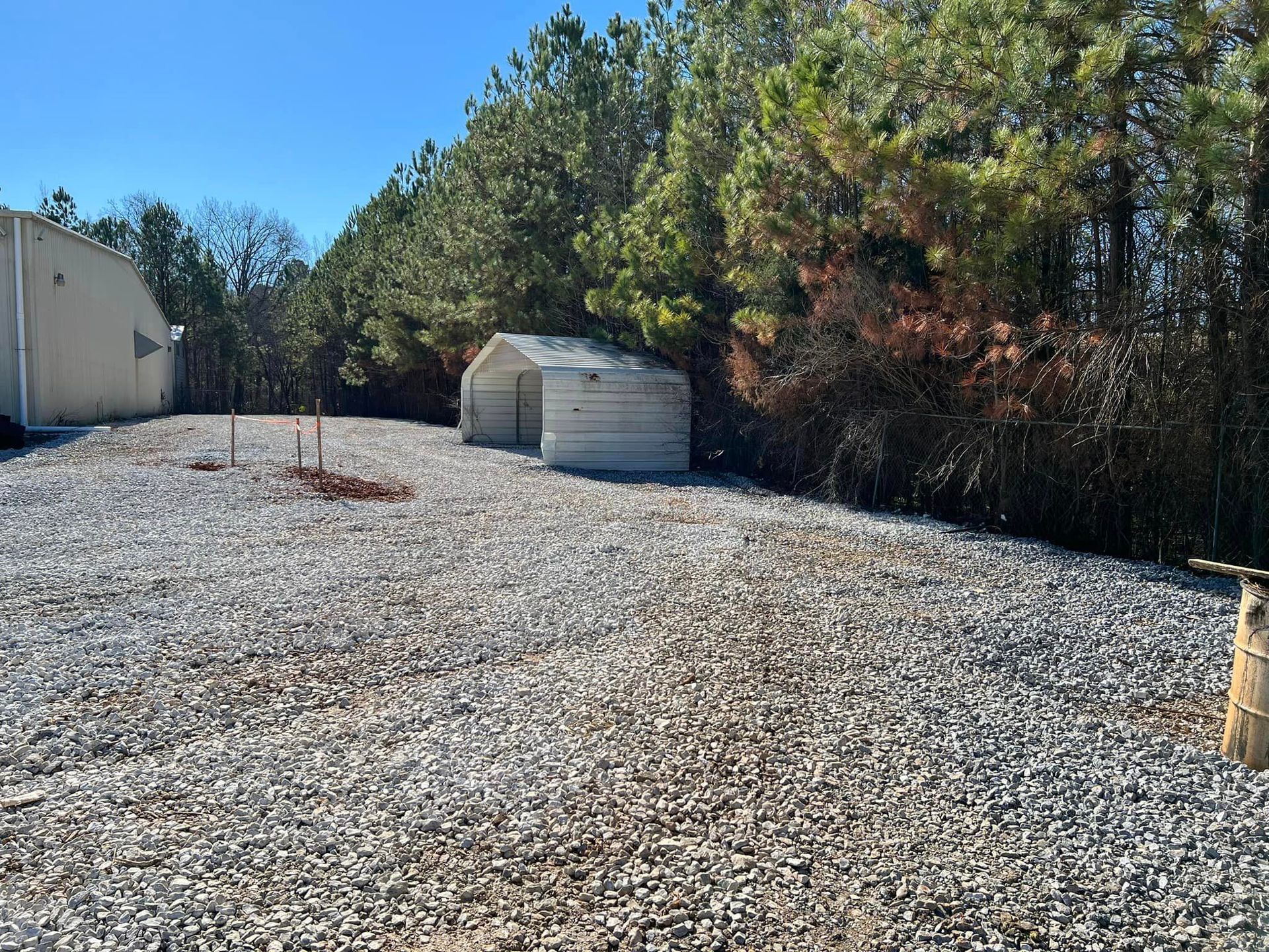 A gravel driveway with a shed in the background