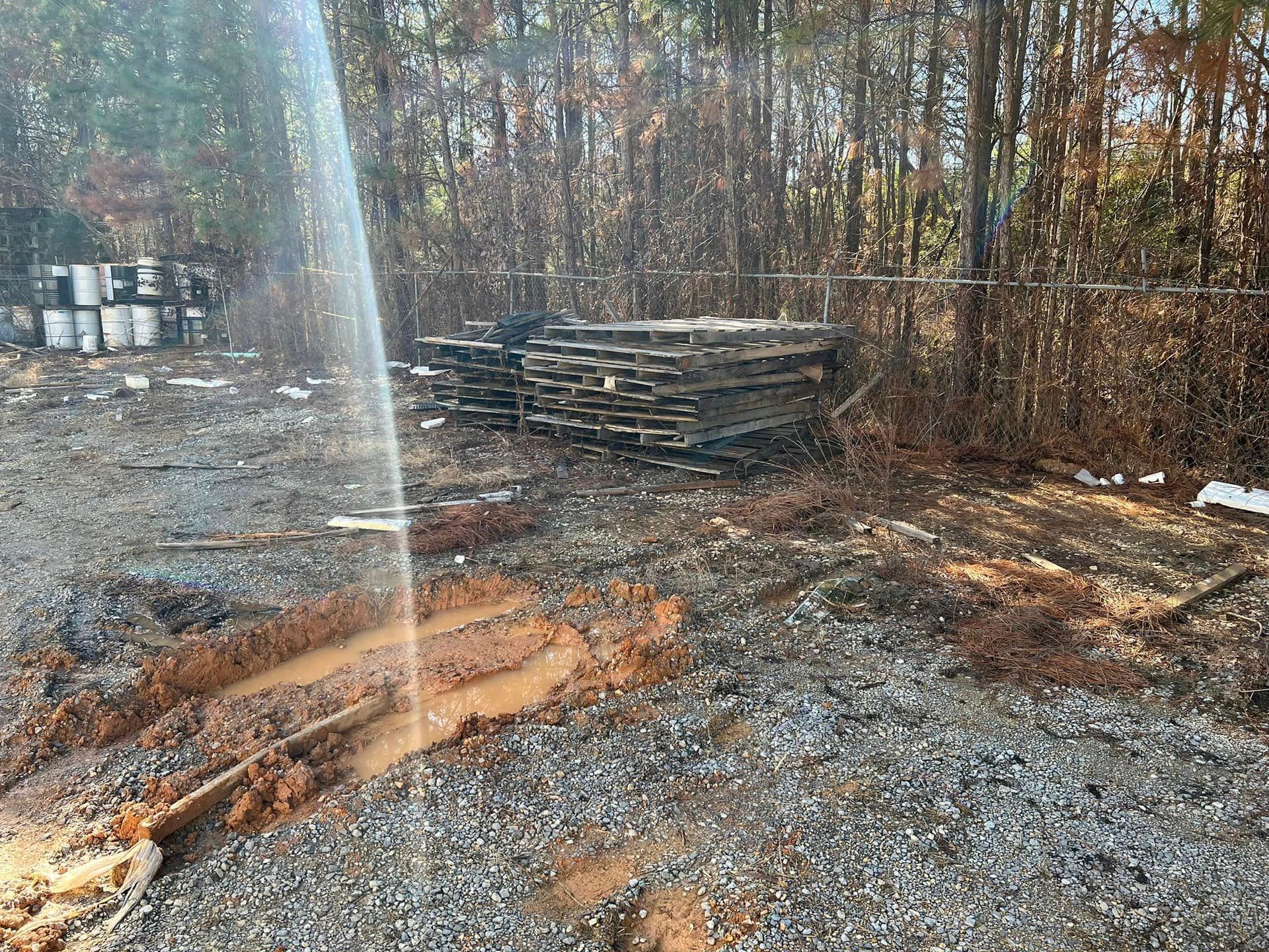 A pile of wood is sitting in the middle of a dirt field.