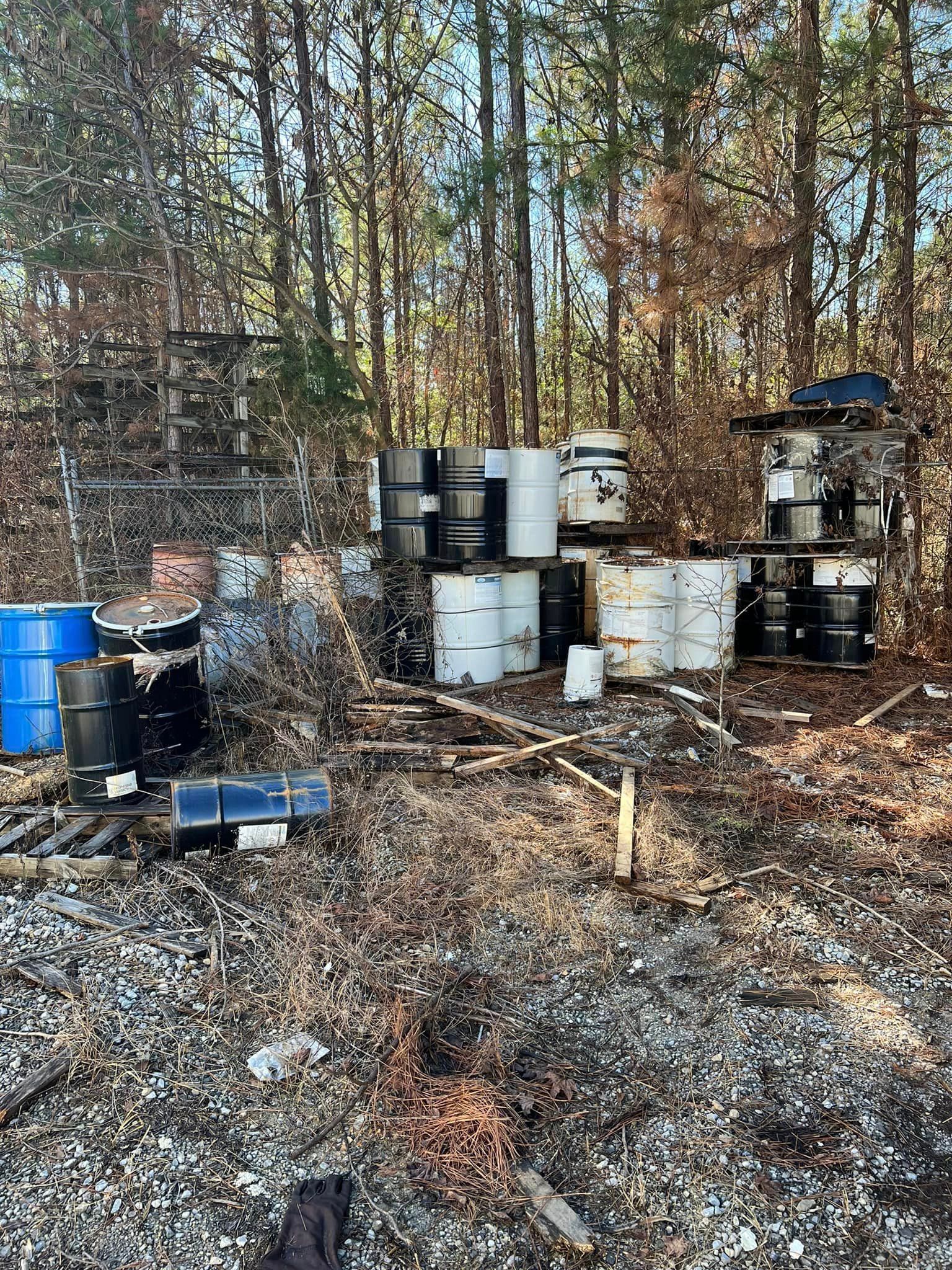 A bunch of barrels are stacked on top of each other in the middle of a forest.