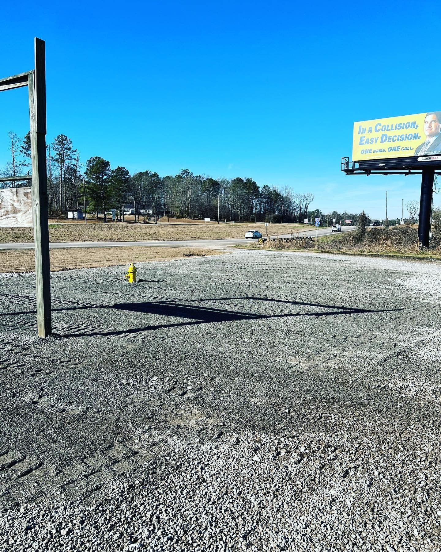 A gravel road with a billboard in the background.