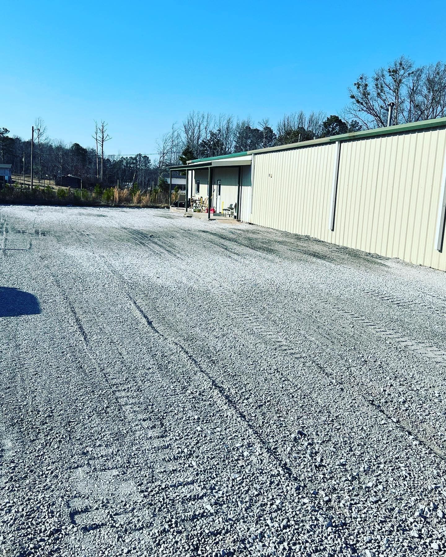 A gravel road leading to a building on a sunny day.