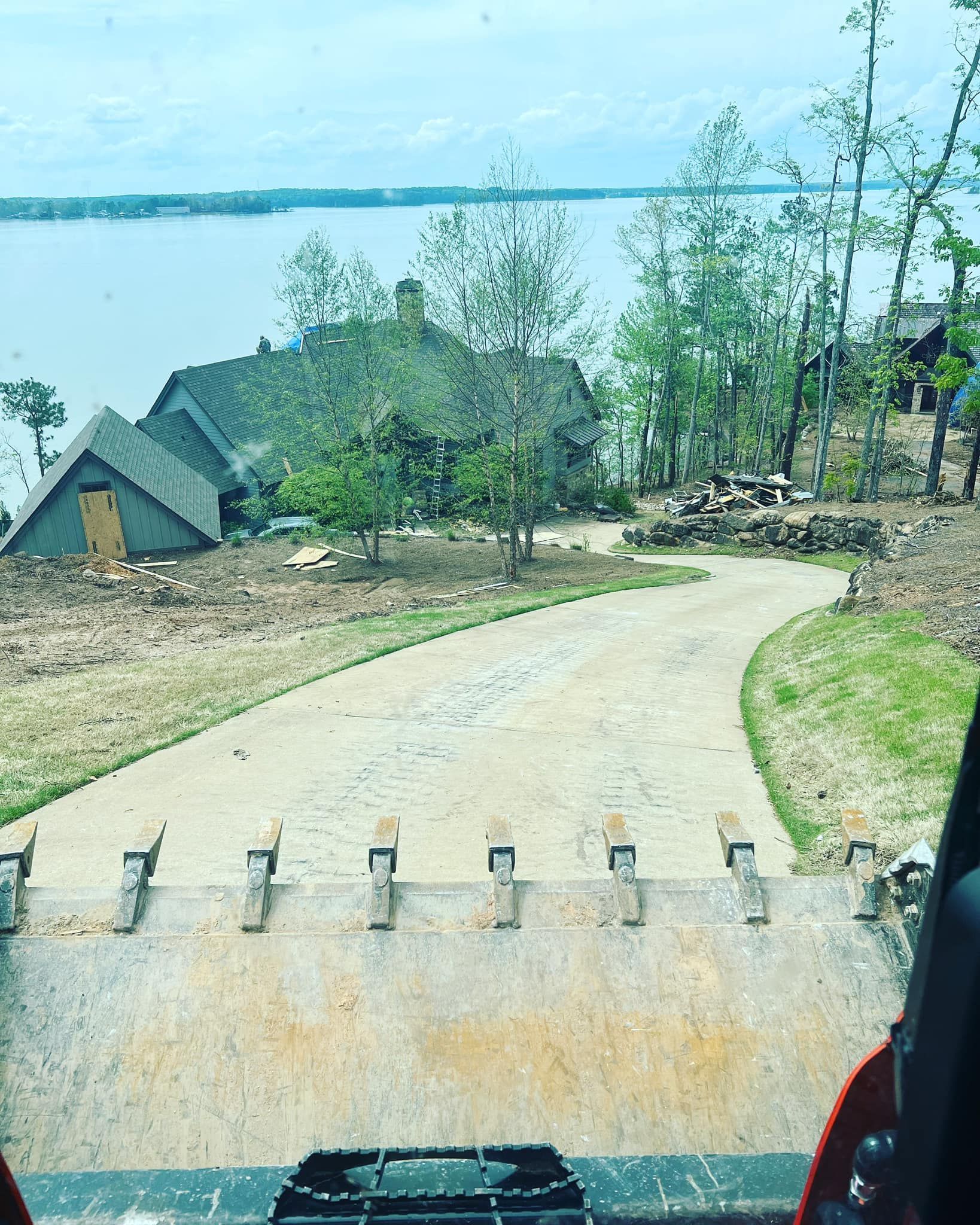 A bulldozer is driving down a dirt road next to a lake.