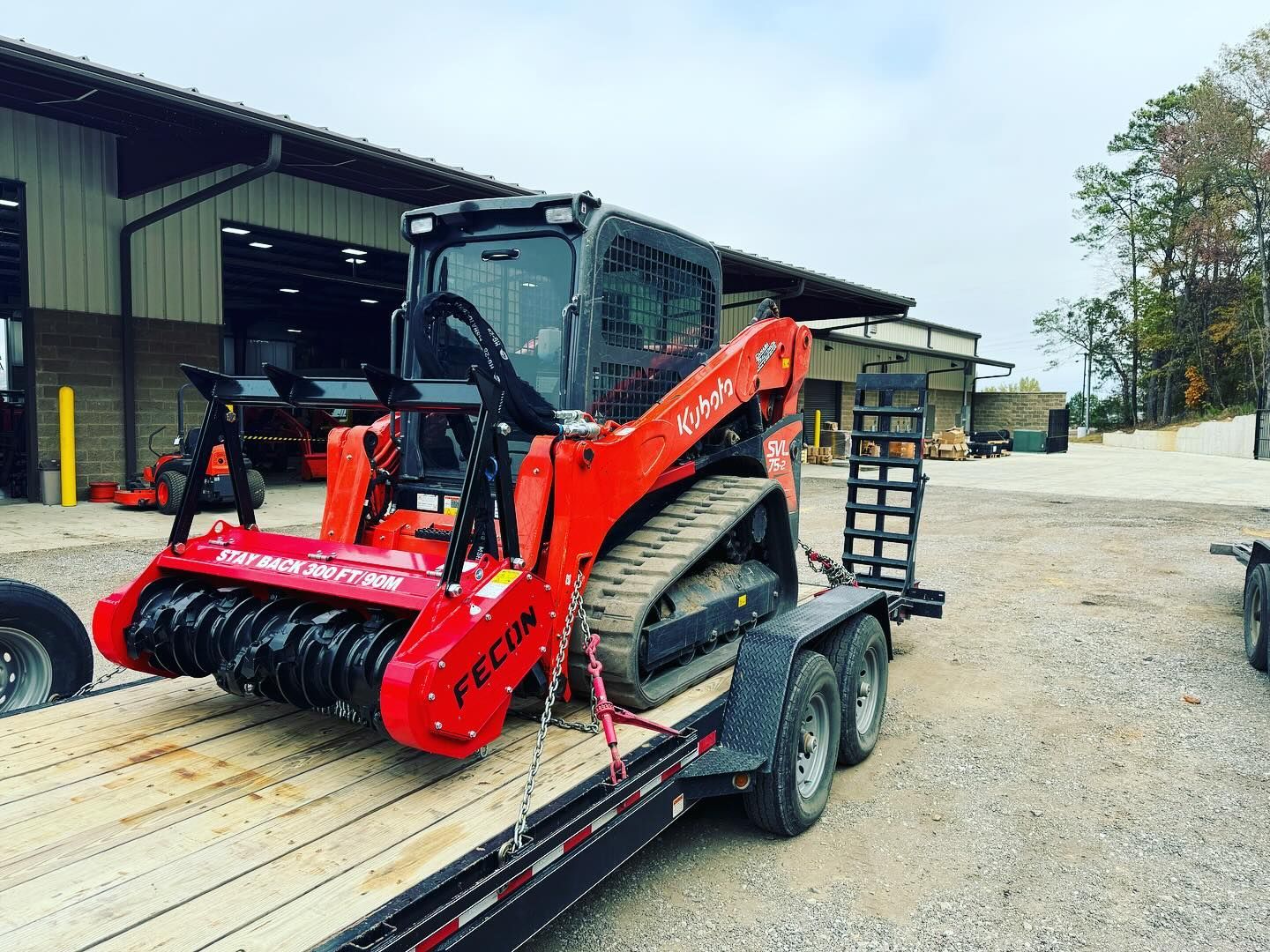 A red tractor is sitting on top of a trailer.
