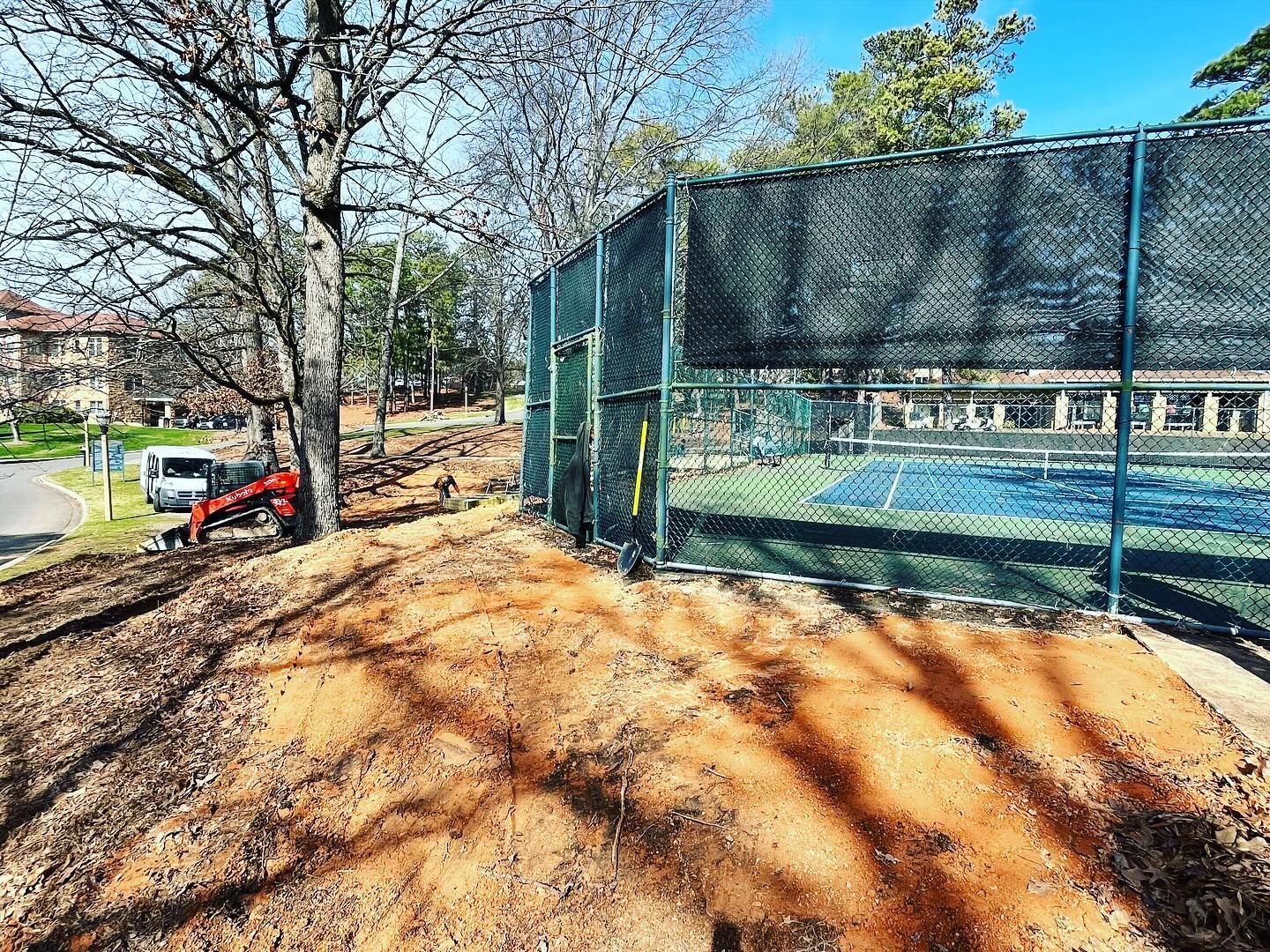 A tennis court is being built next to a fence.