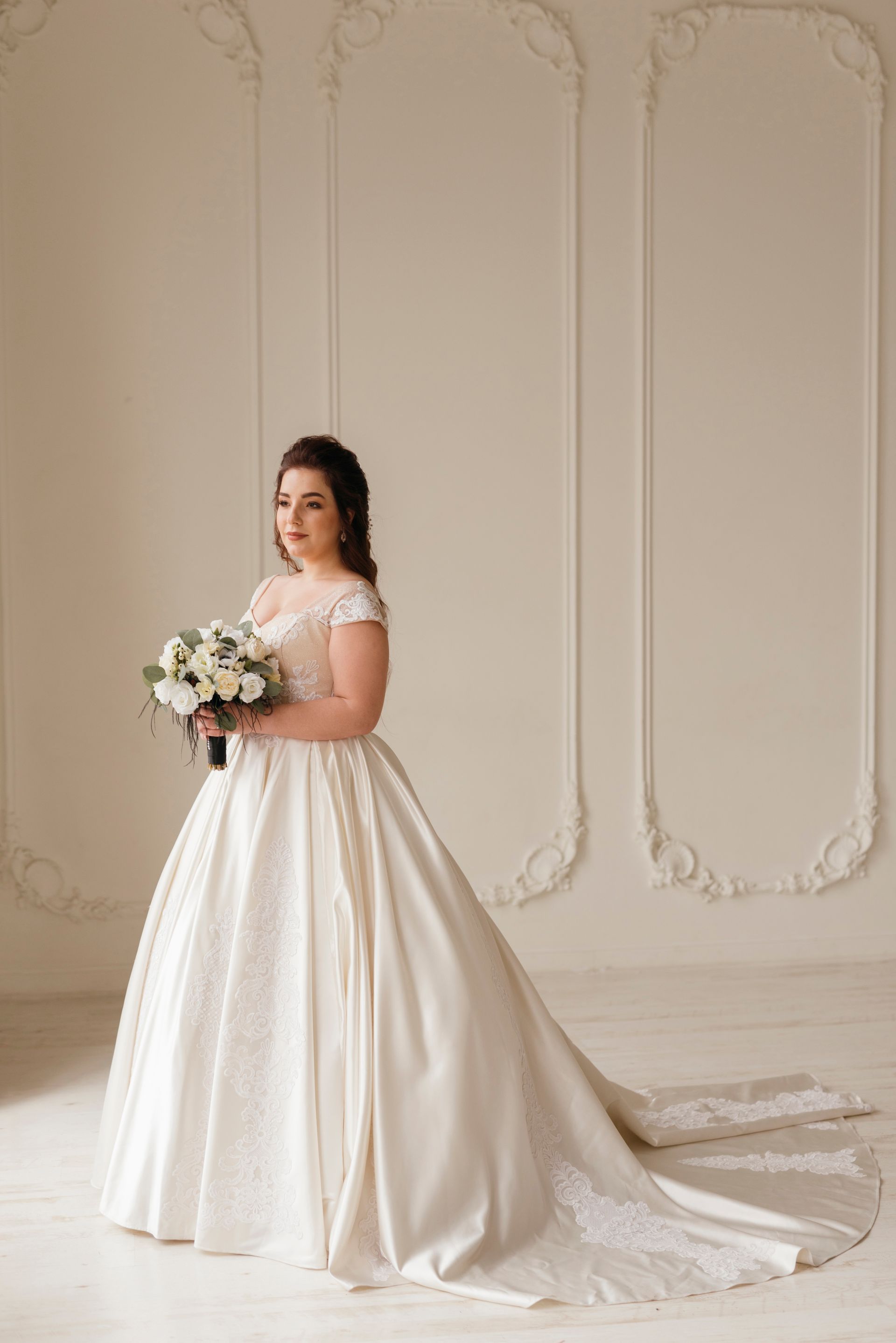 A woman in a wedding dress is standing in a field with mountains in the background.
