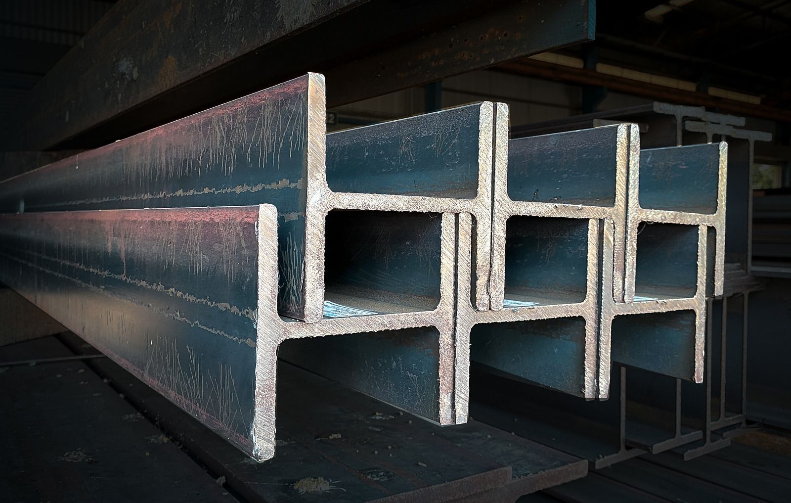 Steel I-beams stacked in a warehouse, ready for construction.