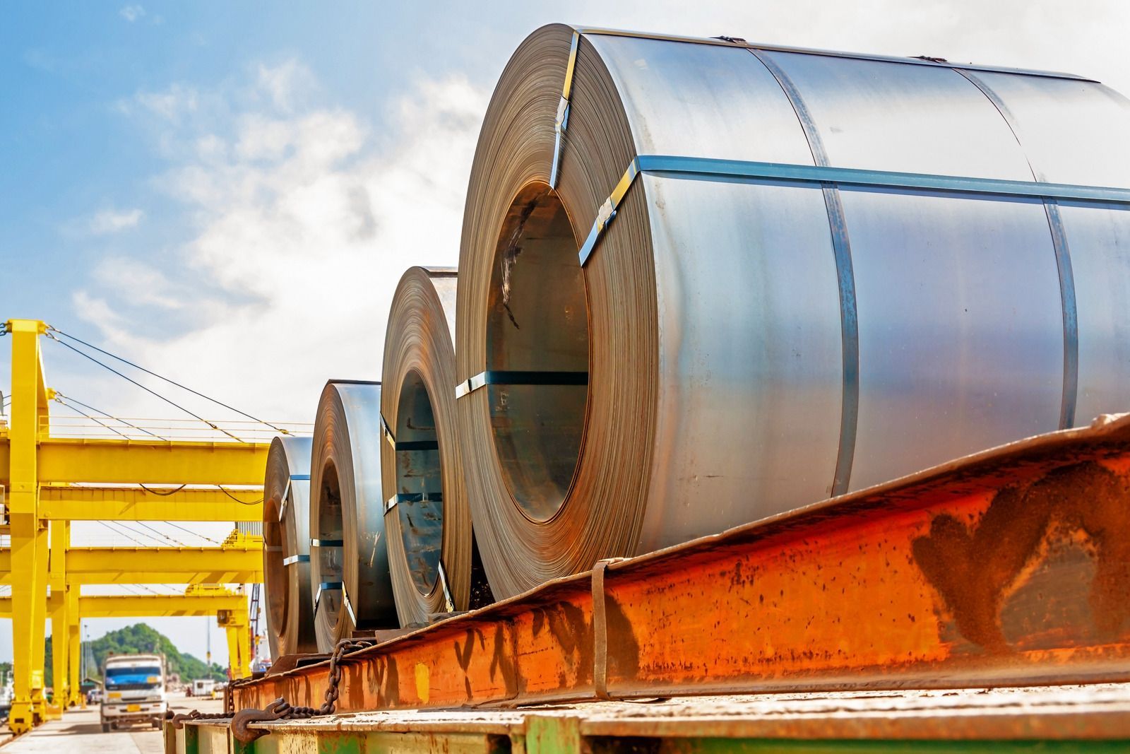 A bunch of steel rolls sitting on top of a metal beam.