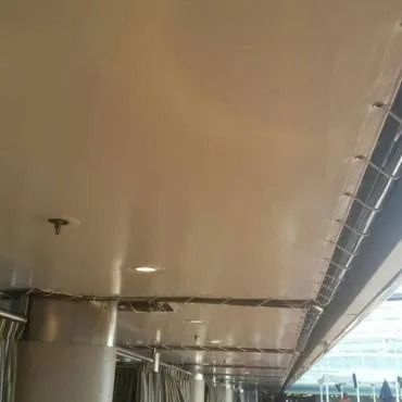 Vista dal basso di un soffitto lucido e di colore chiaro con luci incassate e una striscia di metallo a vista.