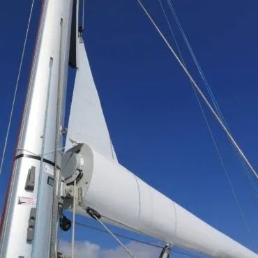 Albero bianco di una barca a vela con vela ammainata contro un cielo azzurro brillante.