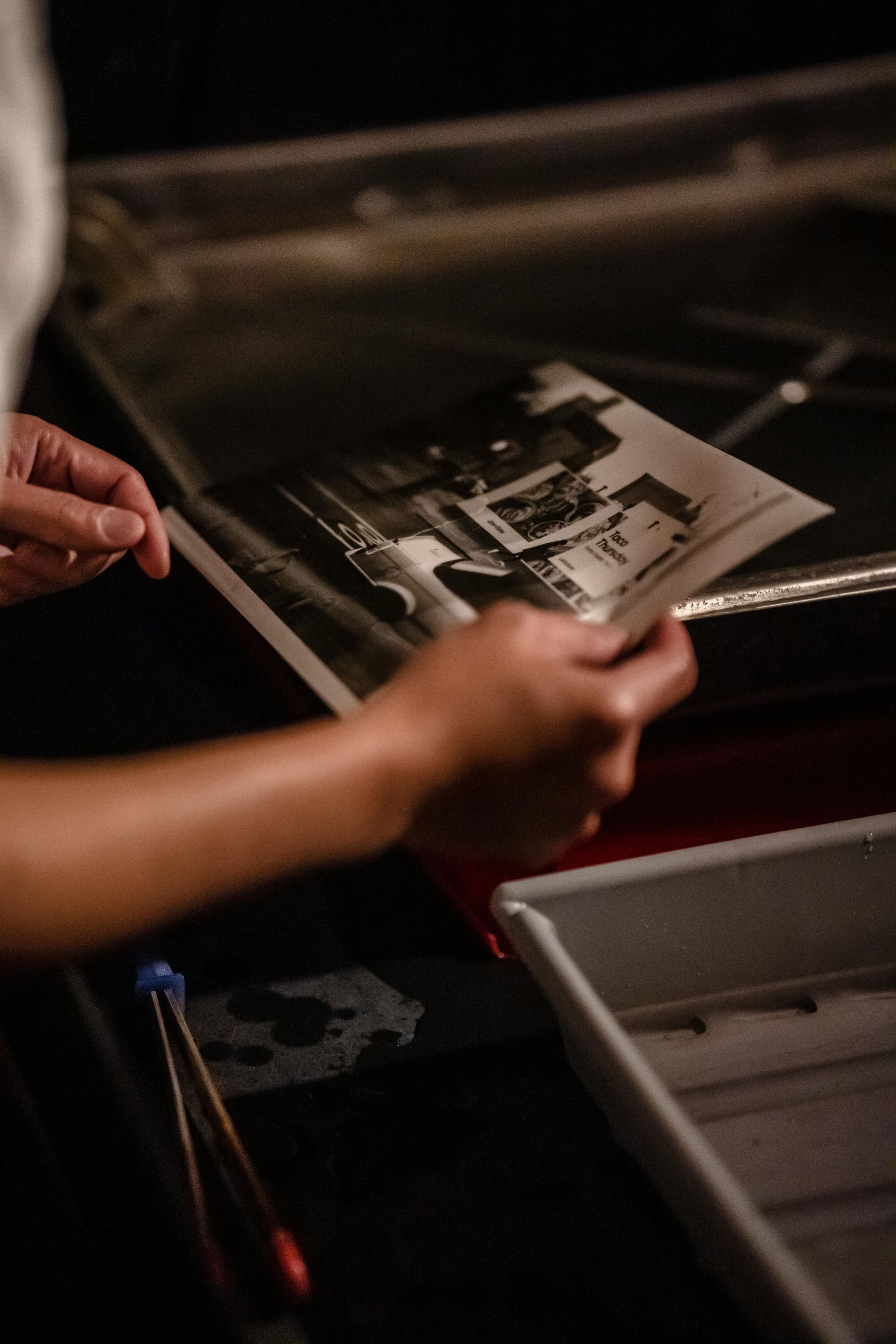 Hand holding a slide with an image of a person with multicolored robes, set against a window backdrop.