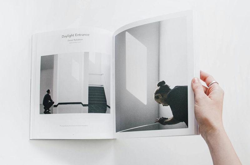 Person holding open book, showcasing black-and-white photos of architectural spaces.