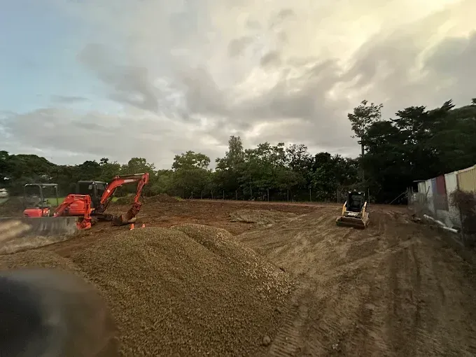 Red Excavator Digging in a dirt field— Cairns Earthmoving Solutions In Smithfield, QLD