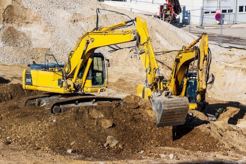 Two Excavators Digging Dirt at a Construction Site — Cairns Earthmoving Solutions In Redlynch, QLD