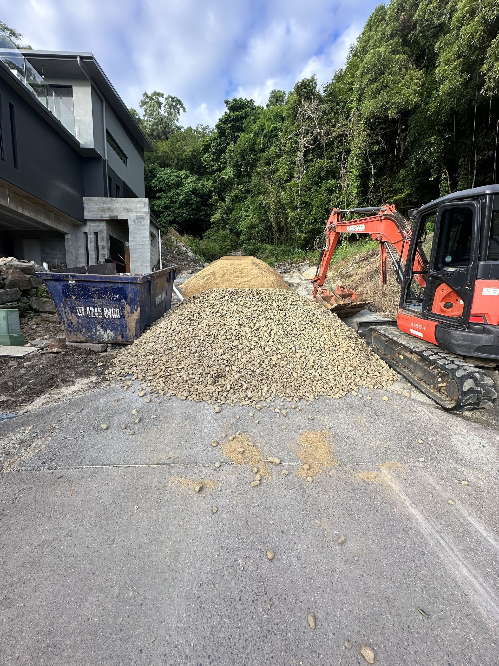 A red excavator is digging a hole in the dirt — Cairns Earthmoving Solutions In Redlynch, QLD