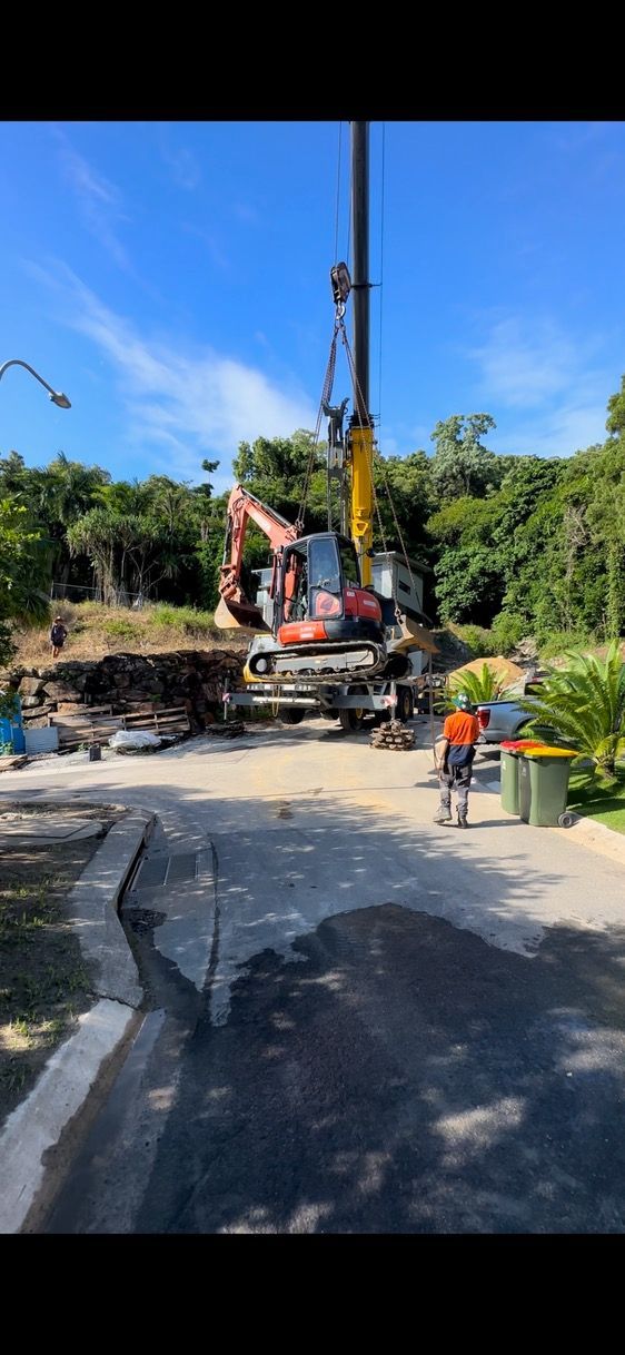 A Yellow Excavator Is Digging A Hole In A Dirt Field — Cairns Earthmoving Solutions In Redlynch, QLD