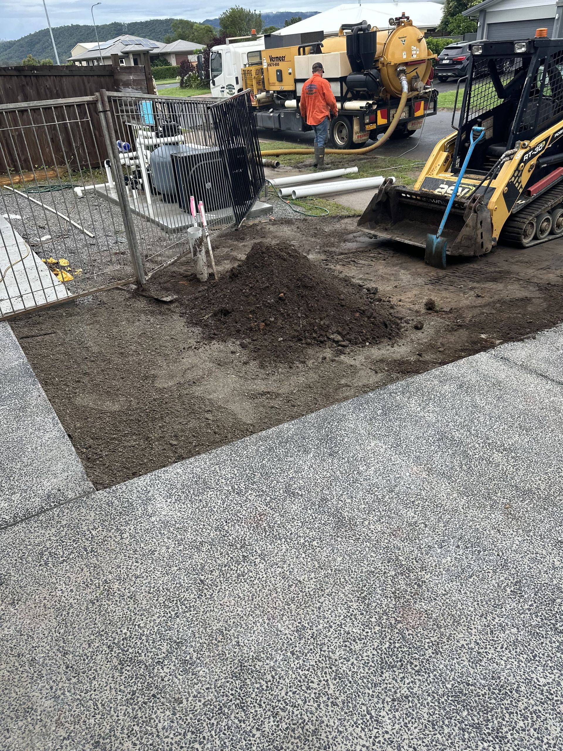 A Yellow Excavator Is Working On A Dirt Grass In The Woods — Cairns Earthmoving Solutions In Redlynch, QLD