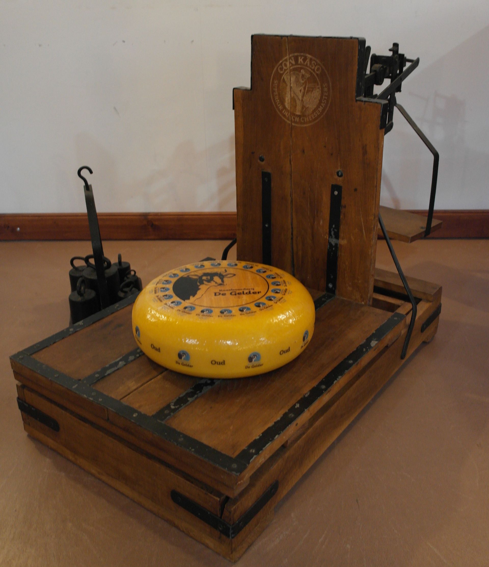 Ein Gouda-Käselaib mit einem abgeschnittenen Stück darauf, auf weißem Untergrund.