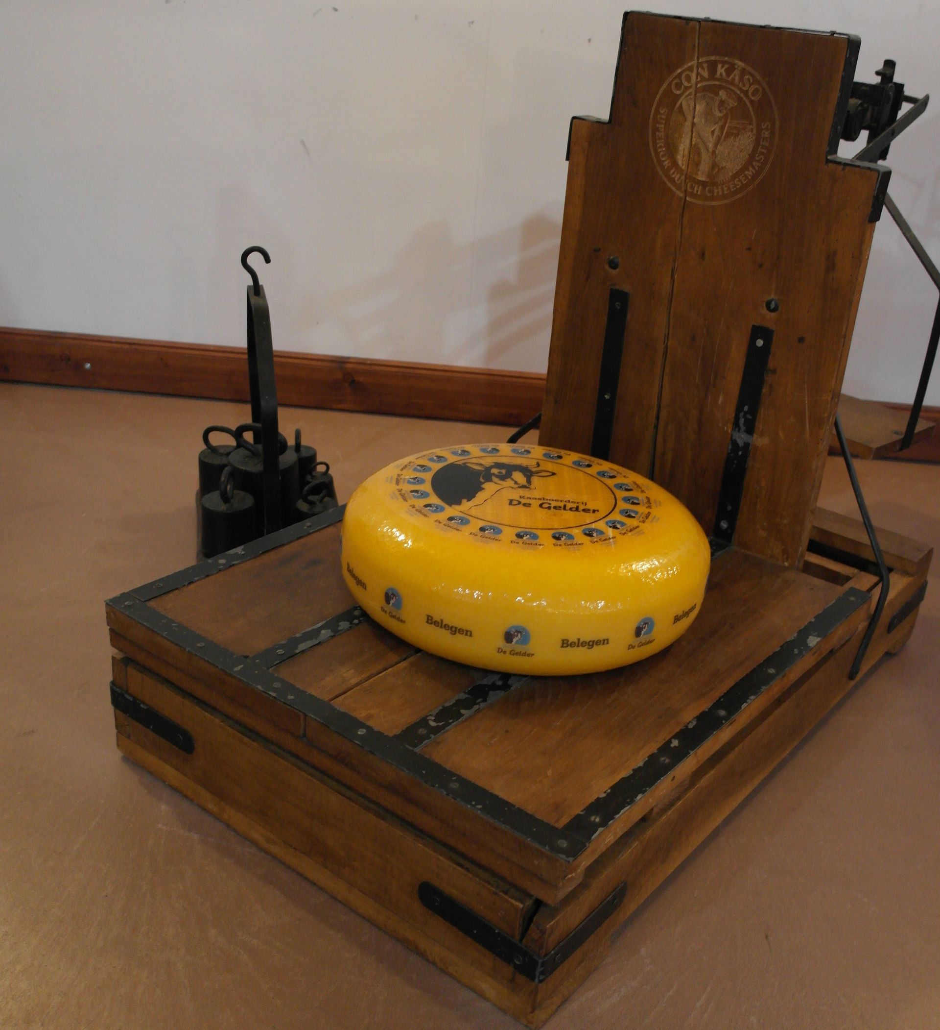 Runder Gouda-Käse mit einem eingeschnittenen Keil obenauf, beschriftet mit „De Gelder“. Gelbe Rinde, helles Inneres.