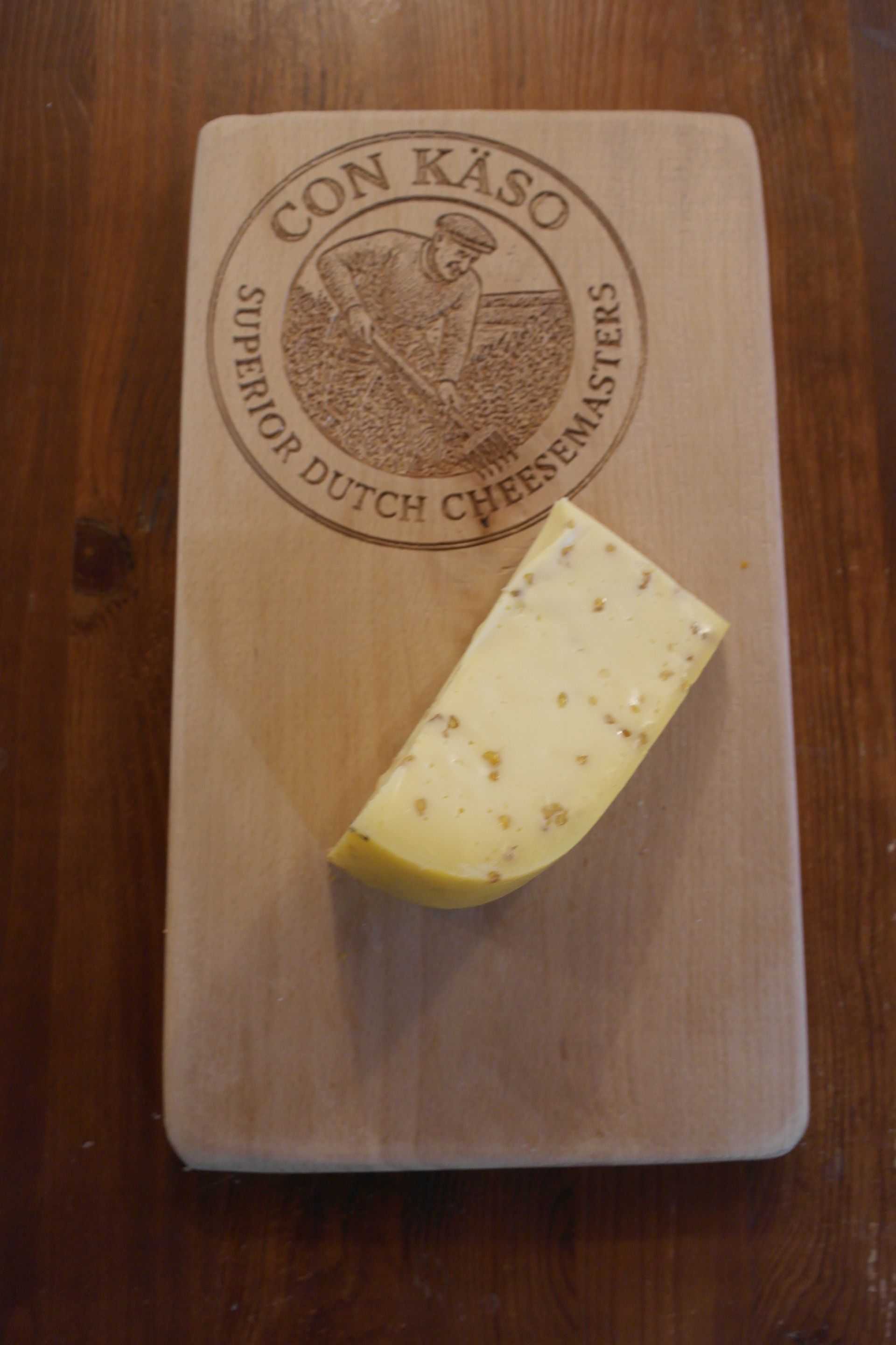 Ein Laib holländischer Käse, „De Gelder“, aus dem ein Stück herausgeschnitten wurde, auf einem weißen Teller.