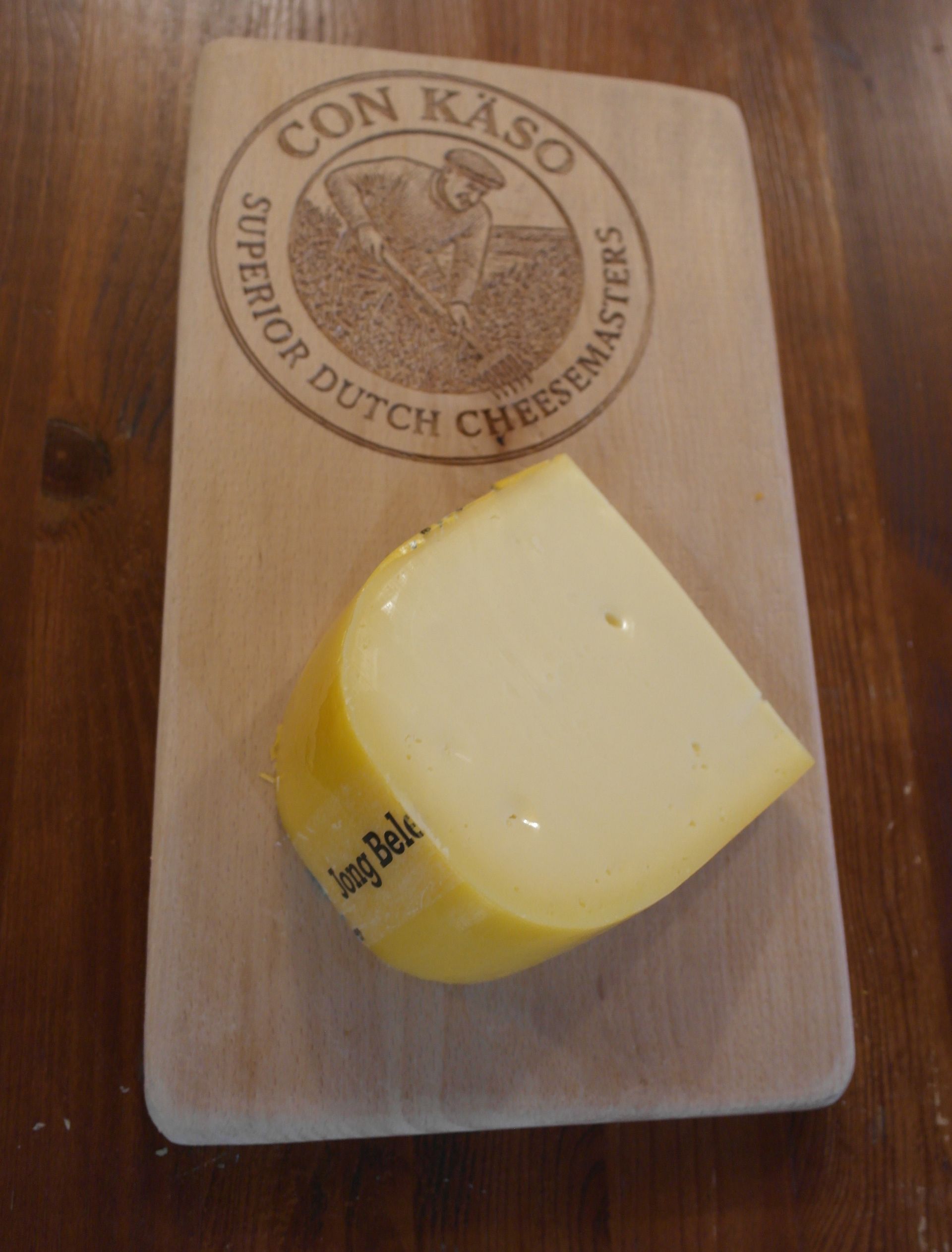 Runder De Gelder Käse mit ausgeschnittenem Keil, goldgelb mit Wachsrinde.