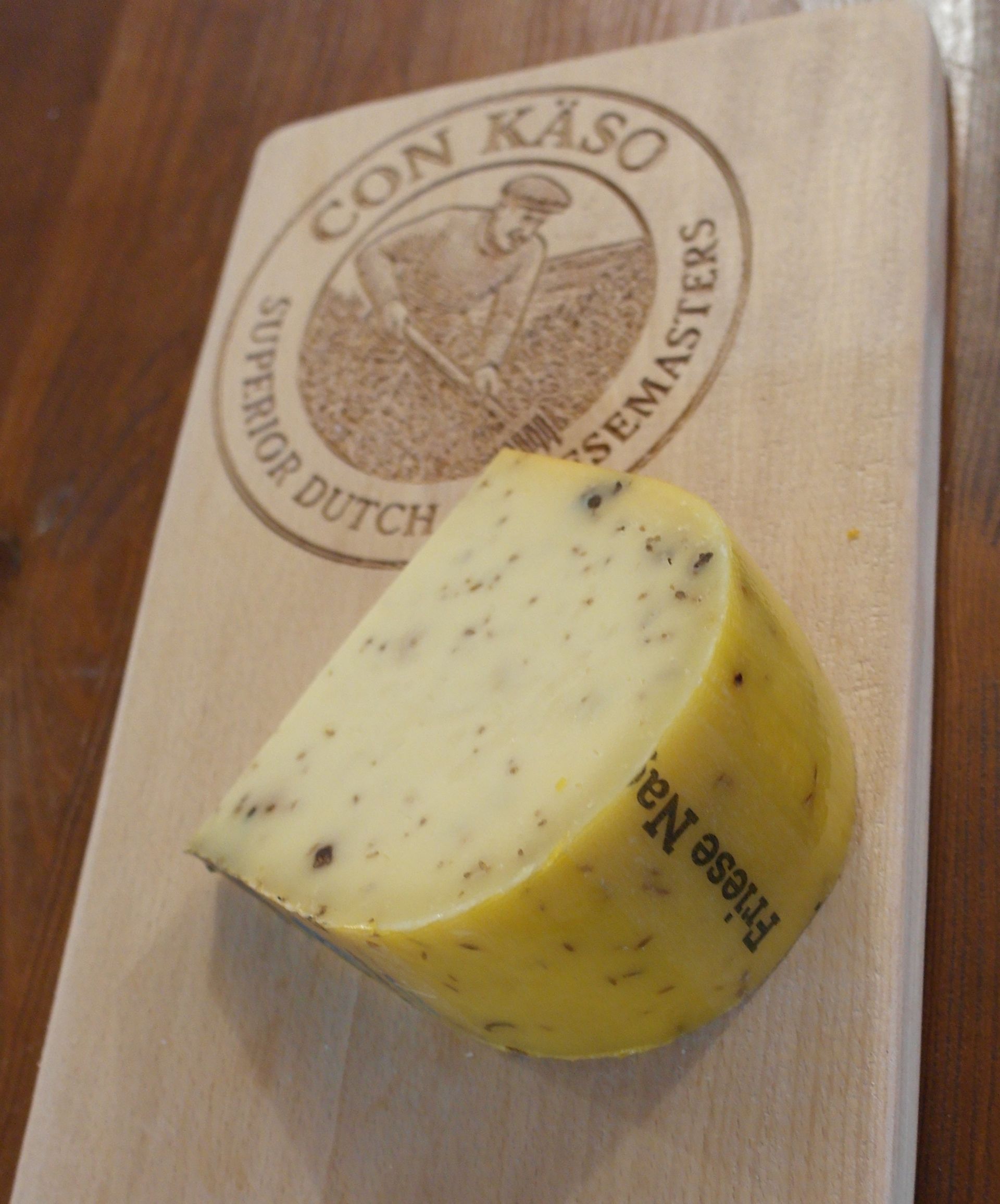 Runder Käselaib, „De Gelder“, mit einem ausgeschnittenen Stück; goldbraun mit Kräutern.