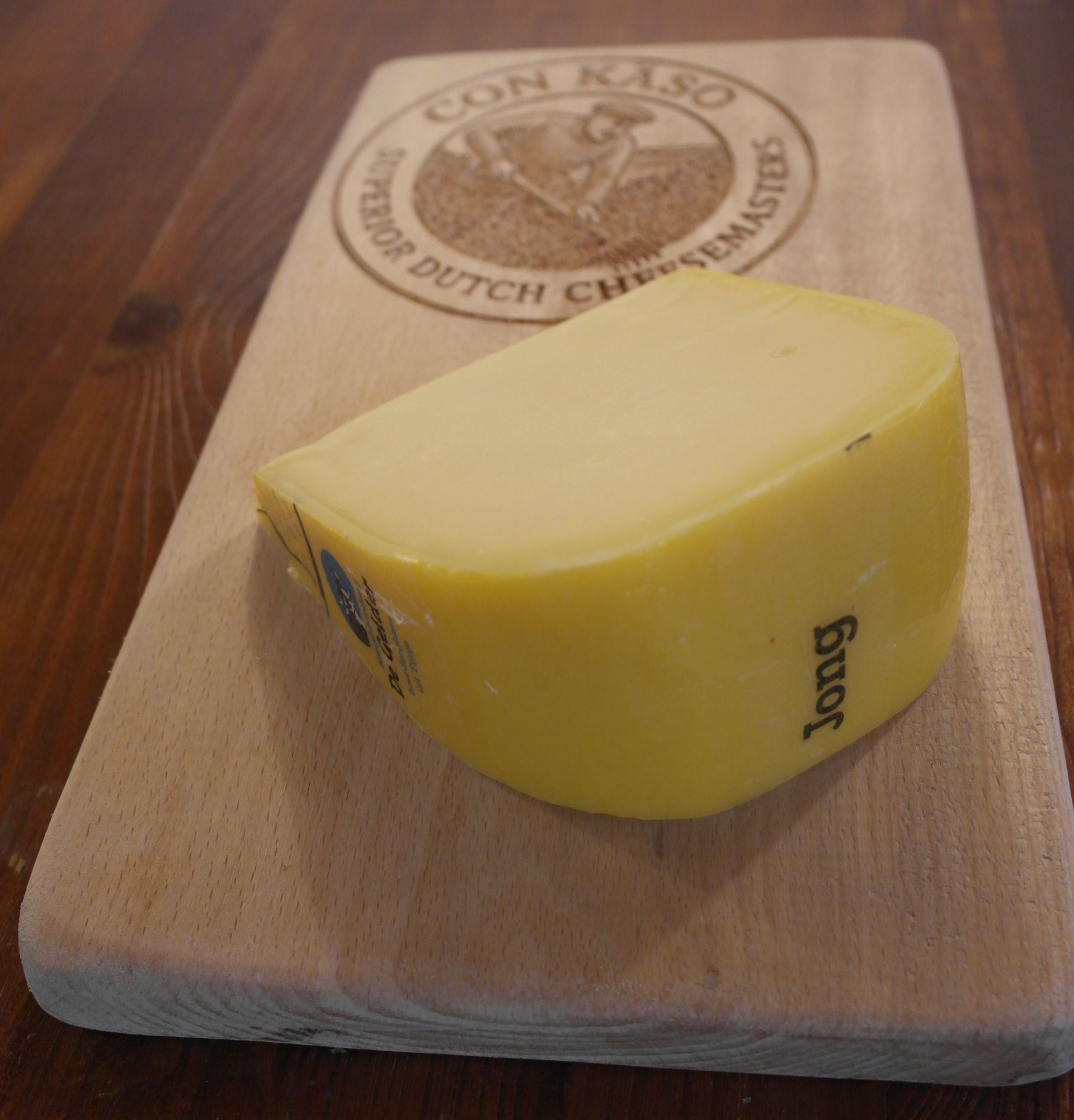 Ein Laib Käse, aus dem ein Stück herausgeschnitten wurde. Gelbe Wachsrinde mit blauen und schwarzen Etiketten.